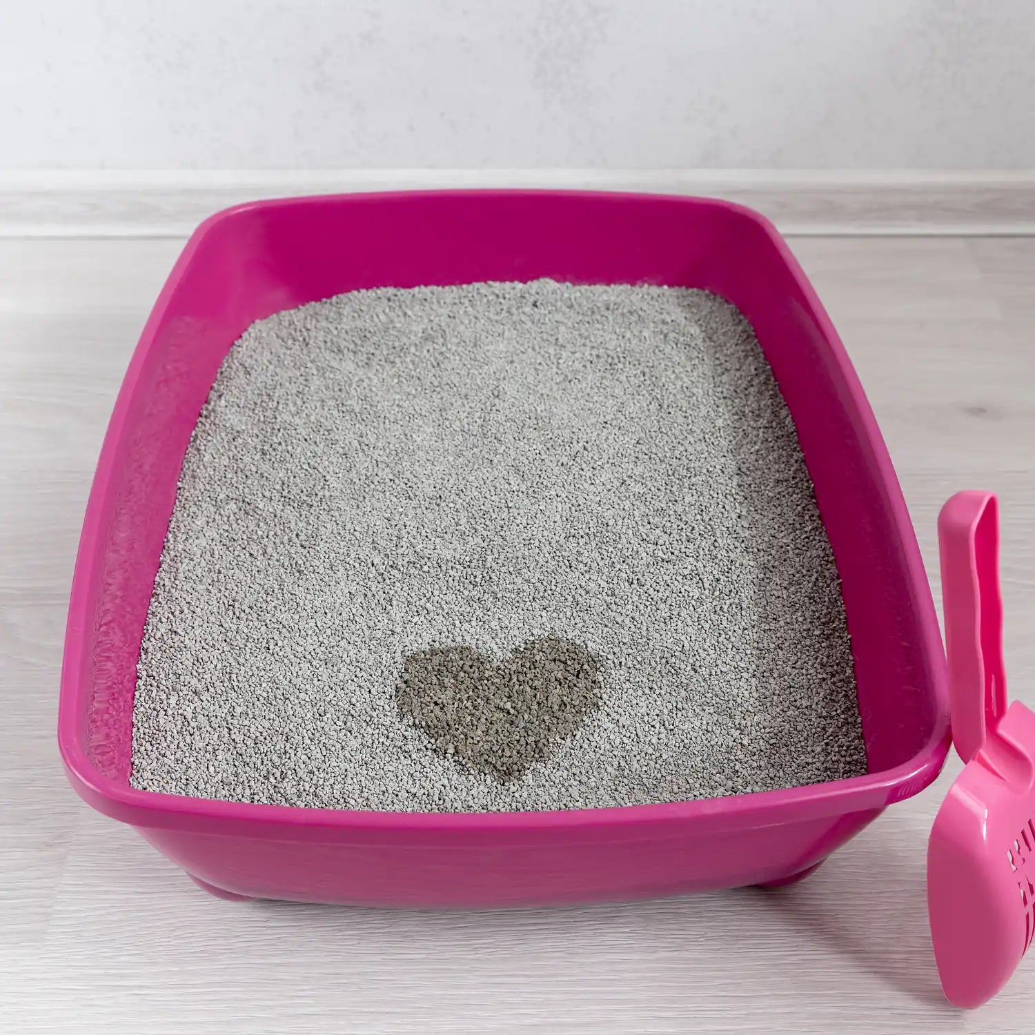 Roze kattenbak met hartvormige klomp.